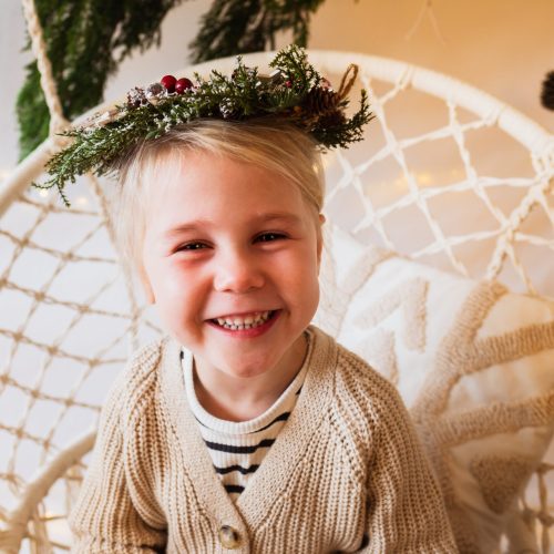 kerstfotografie van een meisje in een schommel met een kerstkrans op haar hoofd